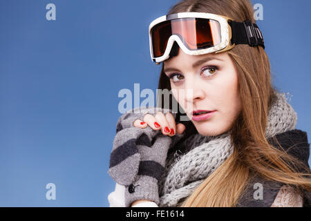 Donna sciatore ragazza di indossare abiti caldi ski googles ritratto. Sport invernali attività. Bella sportive su blue studio shot Foto Stock