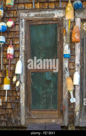 La Costa Centrale; Maine: Weathered porte e parete ricoperta con aragosta boe Foto Stock