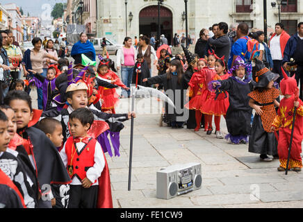 I bambini in costume dancing e marciando per la riproduzione di musica da una boom box in un Halloween Parade, città di Oaxaca, Oaxaca, Messico Foto Stock