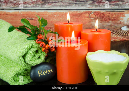 Masterizzazione di candele arancione, sale minerale,arancio berry, pietra lavica e asciugamano still life Foto Stock