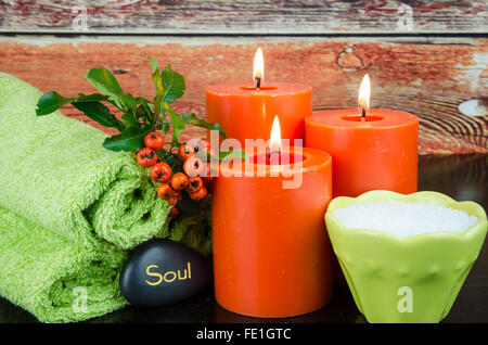 Masterizzazione di candele arancione, sale minerale,arancio berry, pietra lavica e asciugamano still life Foto Stock