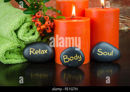 Masterizzazione di candele arancione,arancio berry, pietra lavica e asciugamano still life Foto Stock