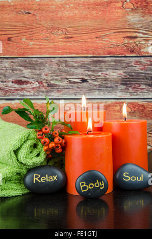 Masterizzazione di candele arancione,arancio berry, pietre laviche e green towel still life Foto Stock