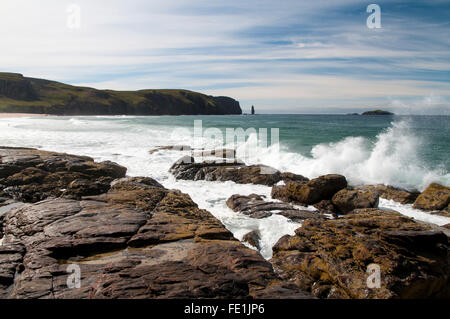 Atlantic di onde che si infrangono sulle rocce Shanabhait Tràigh, la spiaggia a Sandwood Bay, con il promontorio di Rubh' un Bhuachaille un Foto Stock