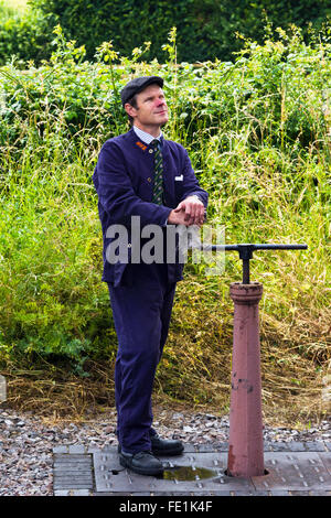 Treno a vapore conducente manning una acqua di rubinetto di arresto/valvola per la colonna di acqua a Watchet stazione sul West Somerset Railway, REGNO UNITO Foto Stock