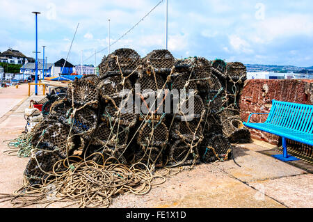 Lobster Pot e attrezzi da pesca ordinatamente impilati sul lato del porto è pronto per essere caricato in un commerciale barca da pesca, Porto di Paignton Foto Stock