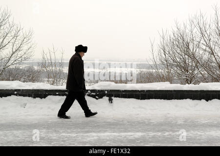 UFA - RUSSIA 16gennaio 2016 - uomo anziano prende una lenta passeggiata lungo una coperta di neve percorso in un parco pubblico in inverno di Ufa, Foto Stock