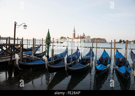 Una fila di nero ormeggiate gondole sulla laguna di Venezia vicino a Piazza San Marco ( Piazza San Marco) a Venezia, Italia. Gondola Foto Stock
