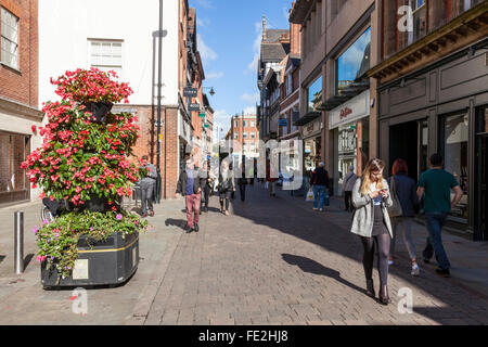 Persona che guarda il telefono cellulare mentre si cammina da altre persone su una strada trafficata, Bridlesmith Gate, Nottingham City Centre, England, Regno Unito Foto Stock