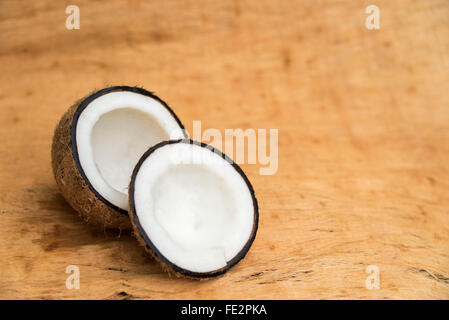 Il vecchio taglio di cocco su sfondo di legno in due parti con lo spazio negativo Foto Stock