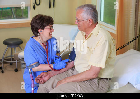 Infermiera con paralisi cerebrale tenendo la pressione sanguigna di un paziente in una clinica Foto Stock