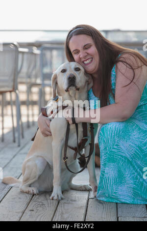 Donna cieca abbracciando il suo cane di servizio Foto Stock
