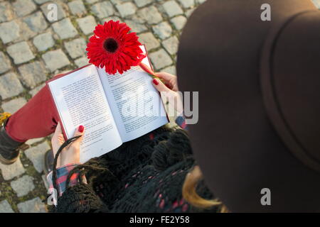 Ragazza romantica con un libro e un rosso fiore di gerbera Foto Stock