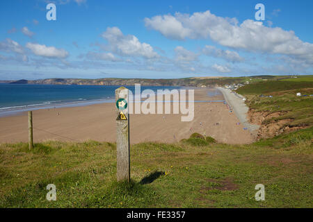 Newgale beach con il cartello con la freccia di direzione e scogliere di pericolo segno Il Pembrokeshire sentiero costiero, West Wales, Regno Unito. Foto Stock
