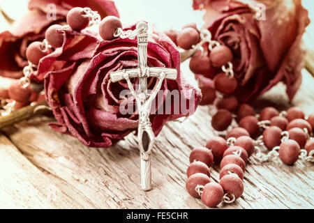Rosario cattolico e asciugare le rose sul vecchio sfondo di legno Foto Stock