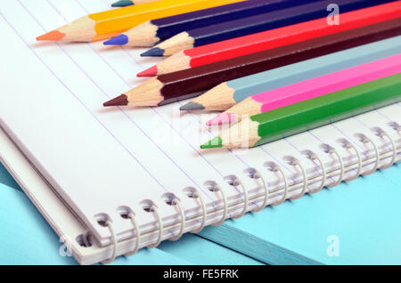 Blocco note e matita colorata blu sul tavolo di legno Foto Stock
