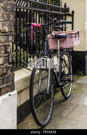 Una bicicletta incatenati contro le ringhiere in ferro in London W10 Foto Stock