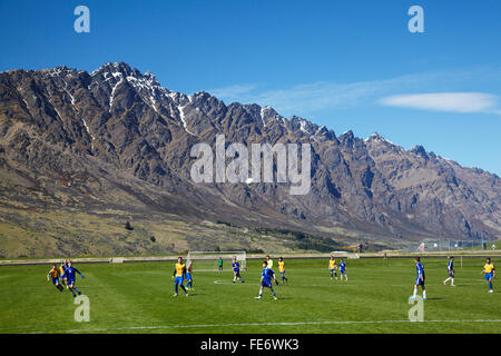 Gioco di Otago Nelson al XIII grado Isola del Sud torneo di calcio, accanto alle montagne Remarkables, Queenstown, Otago, NZ Foto Stock