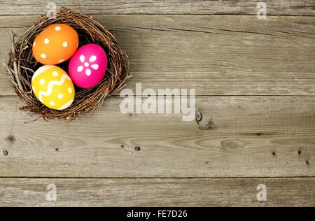 Uova di Pasqua in un nido su un sfondo di legno vecchio Foto Stock