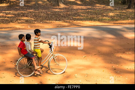 3 giovani ragazzi cambogiani in età scolare si divertono in bicicletta, Siem Reap, Cambogia Foto Stock