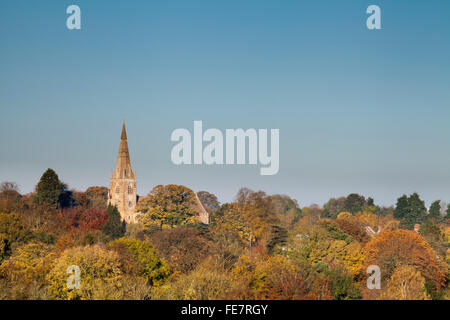 Il Sassone chiesa di Tutti i Santi che si eleva al di sopra degli alberi di autunno nel villaggio di Brixworth nel Northamptonshire, Inghilterra. Foto Stock