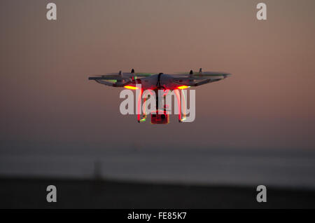 Drone quadcopter volare al tramonto vicino al mare Foto Stock