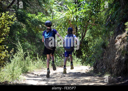 Un ragazzo e una ragazza saltando il primo giorno a piedi il Queen Charlotte Track, Marlborough, Nuova Zelanda Foto Stock