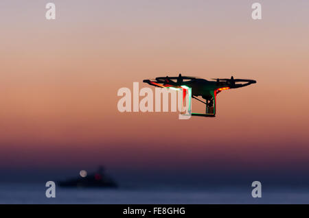 Drone quadcopter volare al tramonto vicino al mare Foto Stock