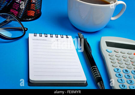 Blocco note con forniture per ufficio su sfondo blu Foto Stock