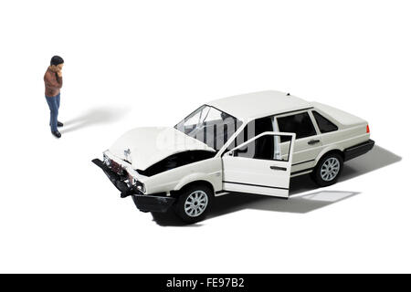 Toy uomo guardando a scatafascio Automobile su uno sfondo bianco Foto Stock