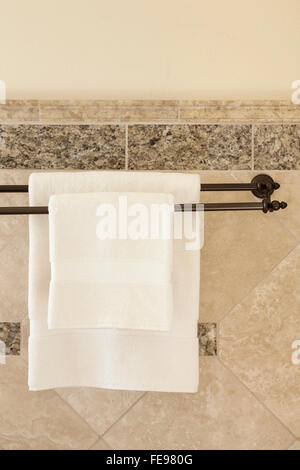 Pulire bianco asciugamani di cotone su bronzo barre di asciugamani in bagno di lusso con mattonelle in pietra pareti. Upscale home particolari degli interni. Foto Stock