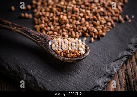 Organici di grano saraceno in cucchiaio nero su sfondo di ardesia Foto Stock