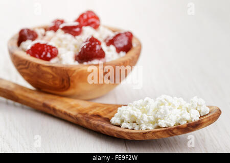 Formaggio con conserva di fragola in ciotola di legno su tavola in legno di quercia Foto Stock