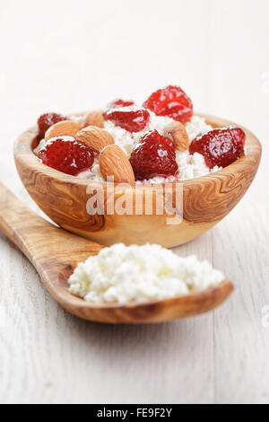 Formaggio con conserva di fragola in ciotola di legno su tavola in legno di quercia Foto Stock