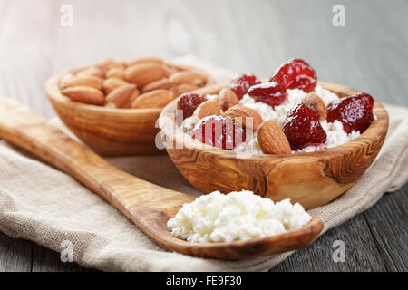 Formaggio con conserva di fragola in ciotola di legno su tavola in legno di quercia Foto Stock