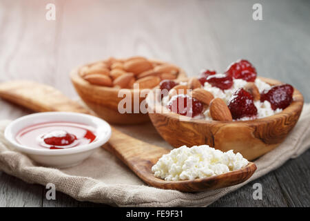 Formaggio con conserva di fragola in ciotola di legno su tavola in legno di quercia Foto Stock