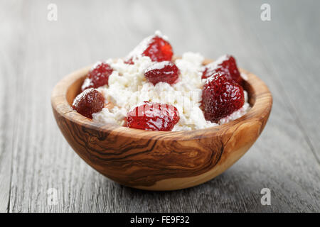 Formaggio con conserva di fragola in ciotola di legno su tavola in legno di quercia Foto Stock