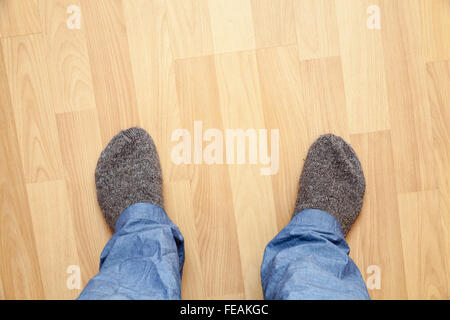 Piedini maschio in pantaloni blu e grigio calze di lana stand sul parquet in legno Foto Stock