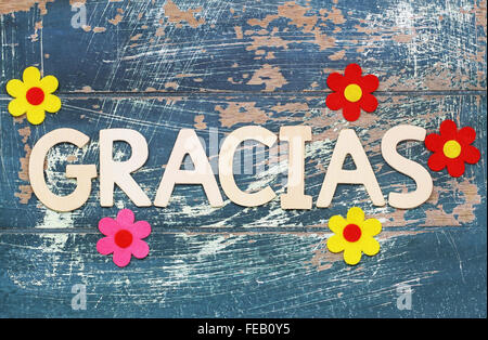 Gracias (grazie in spagnolo) scritto con lettere di legno sulla superficie di rustico e fiori colorati Foto Stock