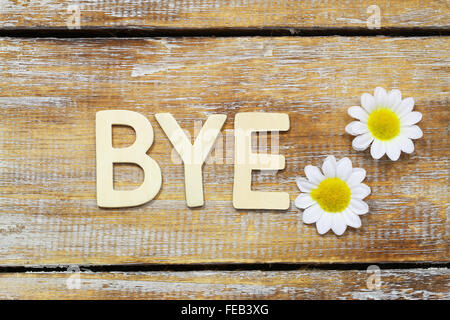 Bye scritto con lettere in legno bianco e fiori a margherita Foto Stock