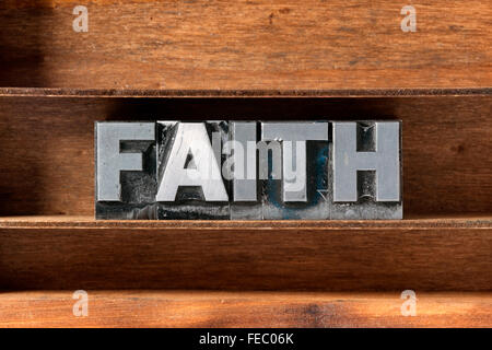 Parola di fede fatta da metallico tipo di stampa in rilievo sul vassoio in legno Foto Stock
