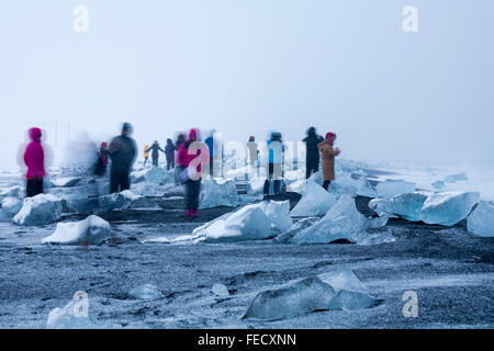 Una lunga esposizione di visitatori i turisti a piedi attorno a Jokulsarlon glaciale, spiaggia spiaggia di Diamante, Islanda nel gennaio Foto Stock