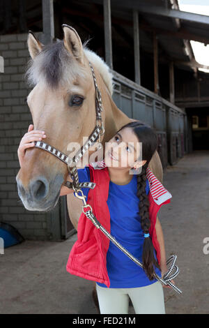 Ritratto di una bambina con il suo pony preferito nella stalla Foto Stock