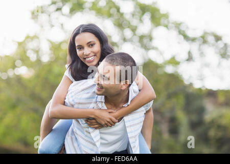 Uomo bello dando piggy back alla sua ragazza Foto Stock