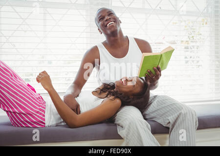 Donna in appoggio sulle gambe oh il suo fidanzato la lettura di un libro Foto Stock