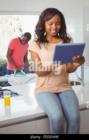 Donna che utilizza tablet mentre il marito utilizzando ferro Foto Stock