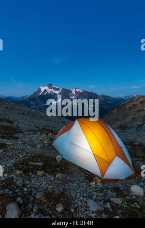 Tenda illuminata da un backpacker con Mt. Shuksan distante, lungo Ptarmigan Ridge nei pressi del Monte Baker, nello Stato di Washington, USA Foto Stock