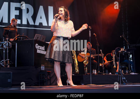 Cantante con un microfono sul palco. Gli uomini che giocano a strumenti nel retro di massa. Foto Stock