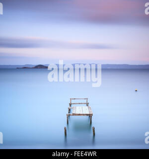 Il molo di legno o molo su un lago blu. Colline sullo sfondo. Fotografie con lunghi tempi di esposizione nel lago di Bolsena, Italia, Europa. Foto Stock