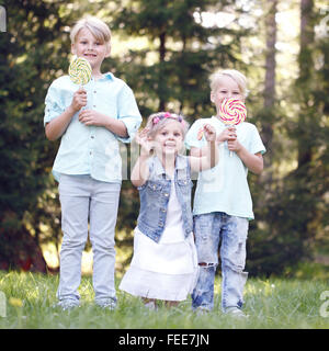 Gruppo di bambini felici di mangiare lecca lecca all'aperto in estate park Foto Stock